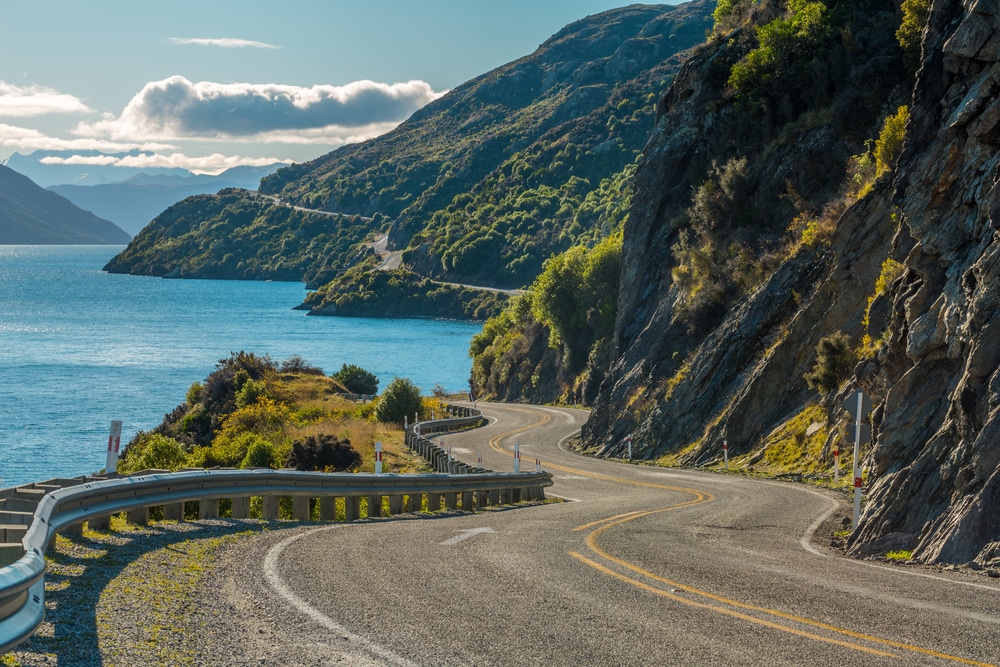 carretera de Nueva Zelanda con lago y montañas verdes