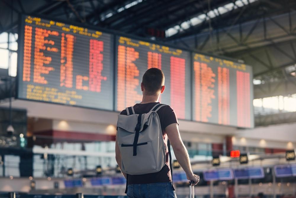 Passager devant un tableau de vols annulés dans un aéroport