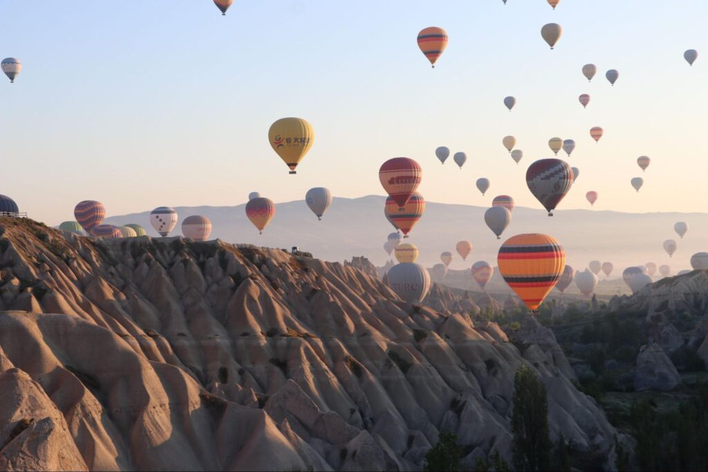 Przelot balonami nad Kapadocją o świcie unoszące się nad skalnymi formacjami i dolinami.