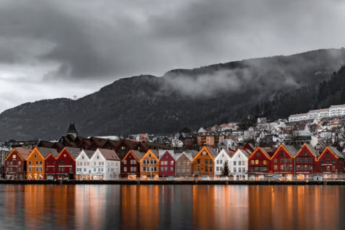 Casas coloridas em Bergen com montanhas ao fundo – melhor altura para ir à Noruega